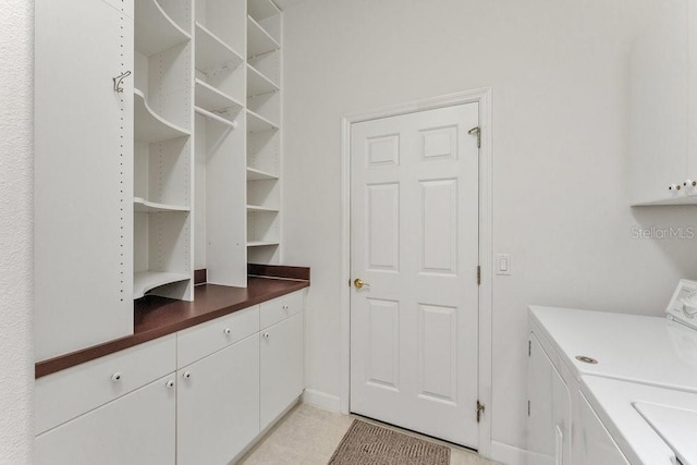 laundry area featuring cabinets, separate washer and dryer, and light tile patterned floors