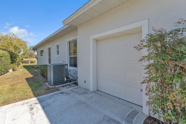 garage featuring a lawn and central AC unit