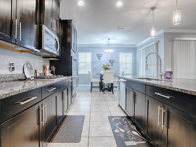 kitchen featuring light stone countertops, sink, decorative light fixtures, dark brown cabinets, and appliances with stainless steel finishes