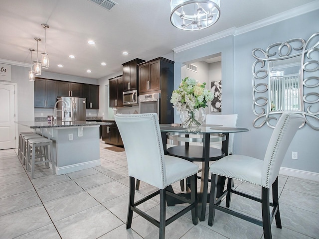 dining area featuring ornamental molding, light tile patterned floors, and an inviting chandelier