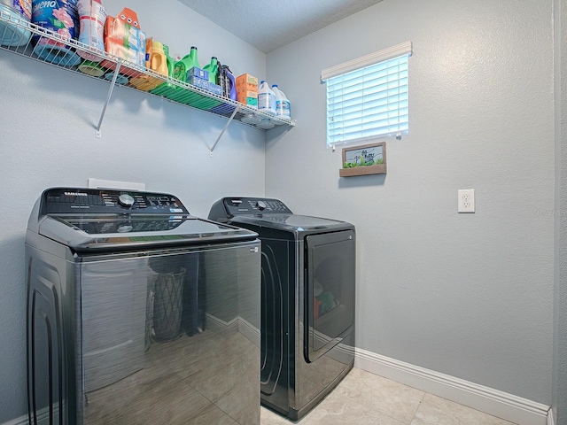 laundry area featuring washing machine and clothes dryer and light tile patterned flooring