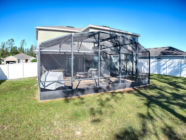 rear view of property with glass enclosure and a yard