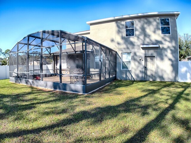 rear view of house with glass enclosure and a yard