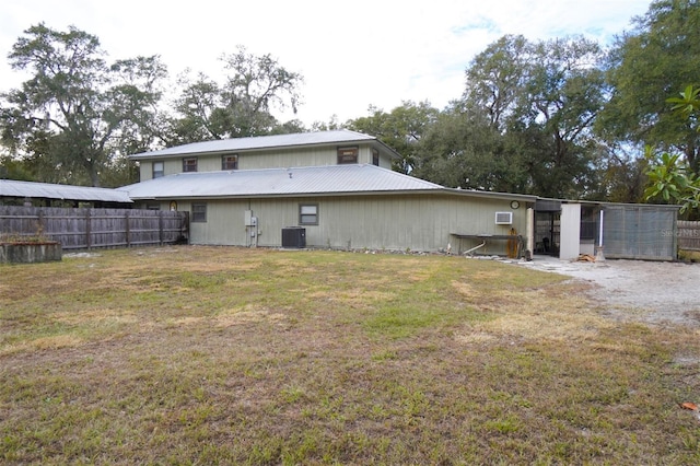 rear view of property featuring a lawn and cooling unit