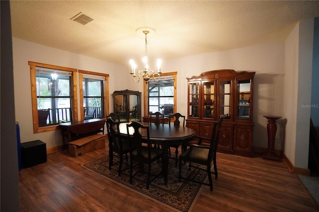 dining space featuring a healthy amount of sunlight, dark wood-type flooring, and an inviting chandelier