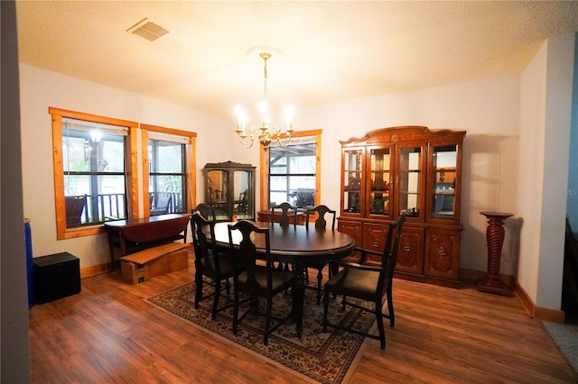 dining area featuring a notable chandelier, dark wood-type flooring, and a healthy amount of sunlight