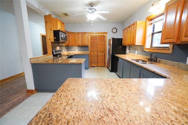 kitchen featuring sink, light stone countertops, ceiling fan, and appliances with stainless steel finishes