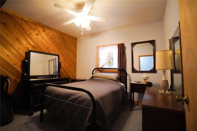 carpeted bedroom with wood walls and ceiling fan