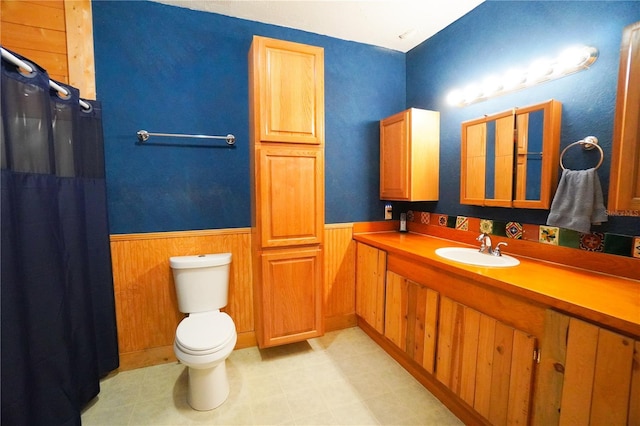 bathroom featuring toilet, wood walls, a shower with shower curtain, and vanity