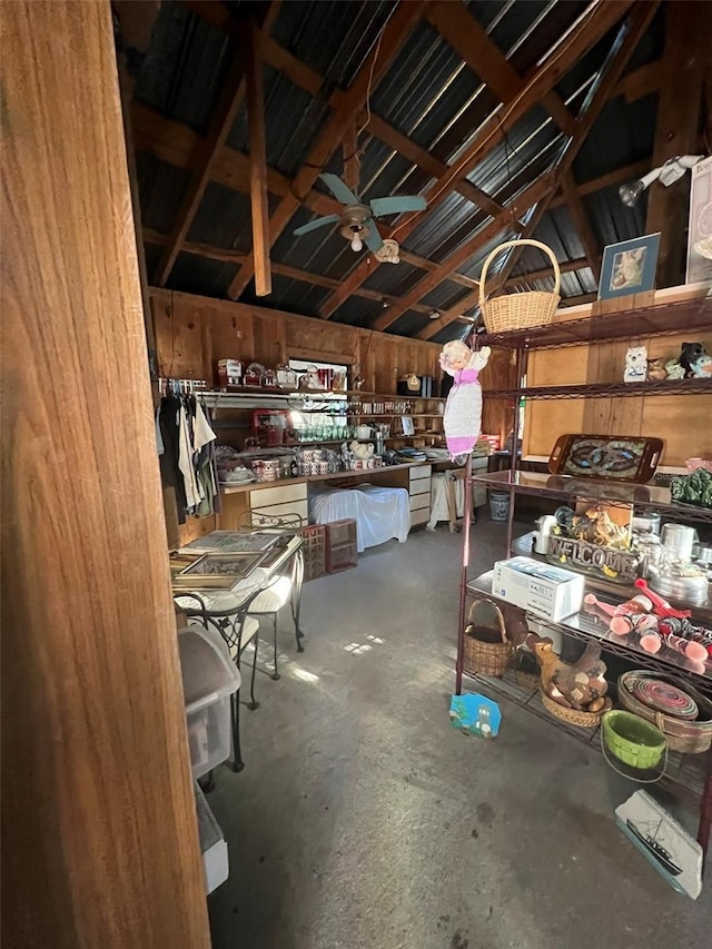 miscellaneous room with lofted ceiling, concrete floors, wood walls, and ceiling fan