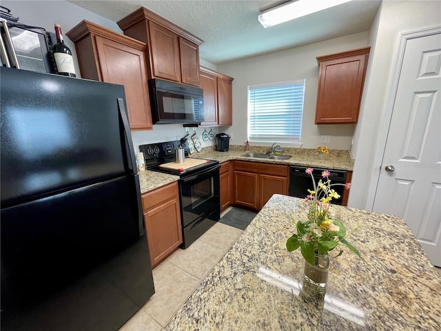 kitchen featuring black appliances, light stone countertops, sink, and a textured ceiling