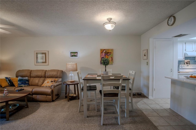 carpeted dining area featuring ceiling fan and a textured ceiling