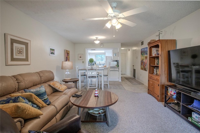 living room featuring light carpet, a textured ceiling, and ceiling fan