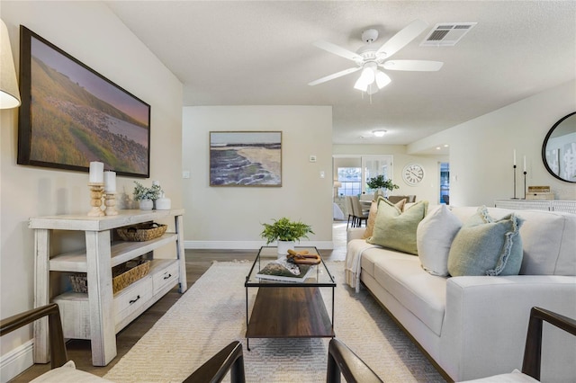 living room featuring a textured ceiling, ceiling fan, and dark wood-type flooring