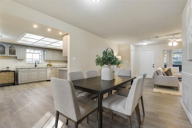 dining space with ceiling fan, a textured ceiling, a wealth of natural light, and light hardwood / wood-style flooring