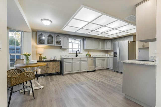 kitchen with gray cabinetry, plenty of natural light, stainless steel appliances, and light wood-type flooring