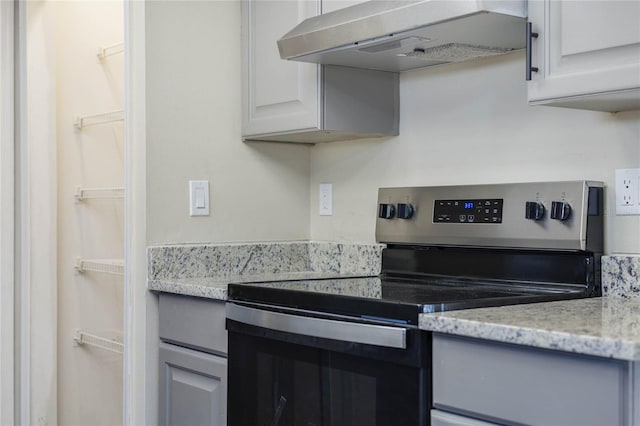 kitchen with light stone countertops, ventilation hood, white cabinetry, and stainless steel range with electric stovetop