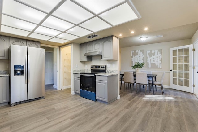 kitchen with gray cabinets, light stone counters, light wood-type flooring, and appliances with stainless steel finishes