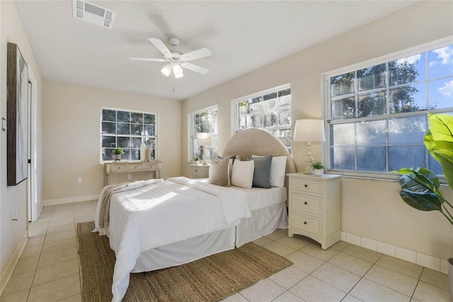 tiled bedroom with ceiling fan and a textured ceiling