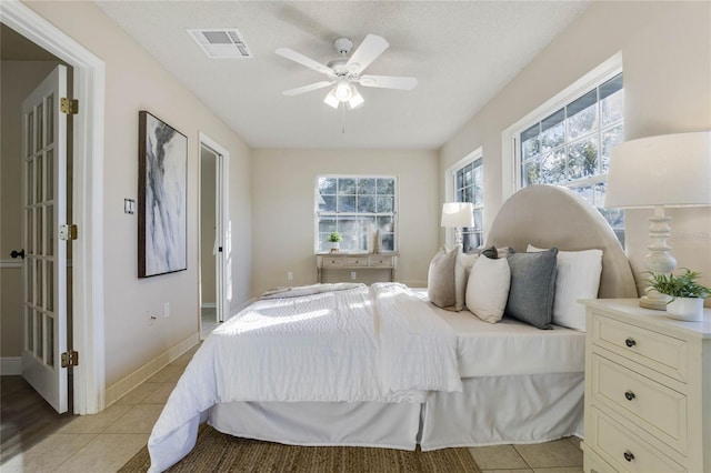 tiled bedroom with ceiling fan and a textured ceiling