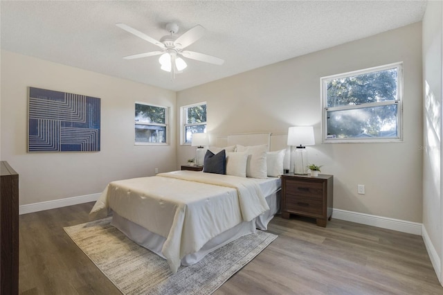 bedroom featuring multiple windows, ceiling fan, a textured ceiling, and hardwood / wood-style flooring