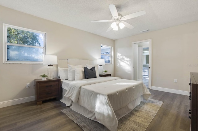 bedroom with a textured ceiling, ceiling fan, and dark wood-type flooring