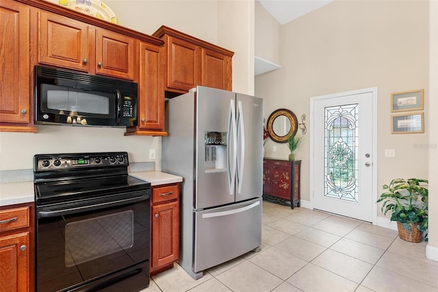 kitchen featuring a towering ceiling, light tile patterned floors, and black appliances