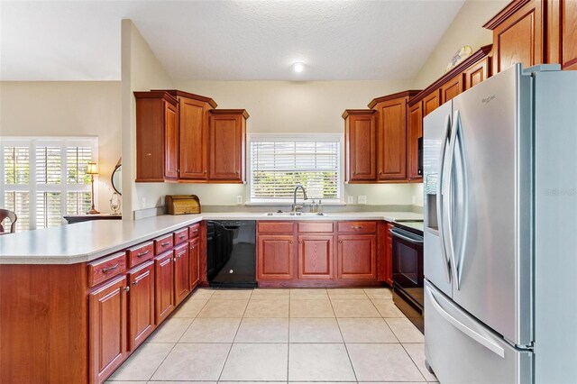 kitchen featuring black appliances, sink, vaulted ceiling, a textured ceiling, and kitchen peninsula