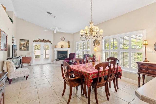 dining space with french doors, light tile patterned floors, ceiling fan with notable chandelier, and high vaulted ceiling