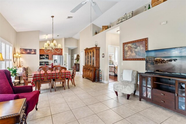 tiled living room with high vaulted ceiling and ceiling fan with notable chandelier