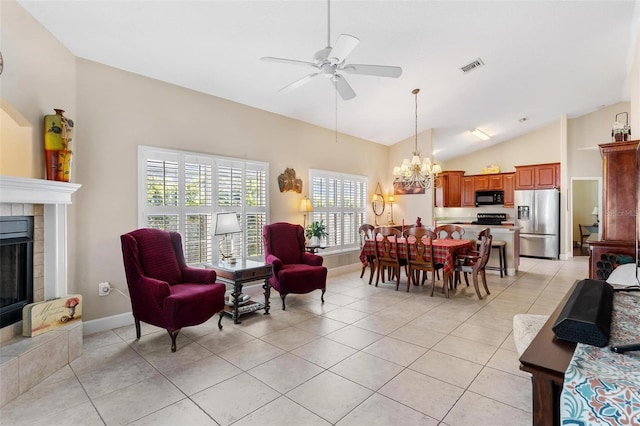 tiled dining room featuring ceiling fan with notable chandelier, lofted ceiling, and a tiled fireplace