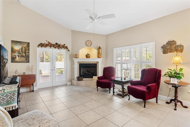 sitting room with a tiled fireplace, ceiling fan, french doors, and light tile patterned floors