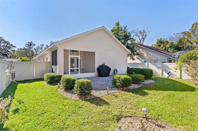 back of property featuring a lawn, a sunroom, and a patio