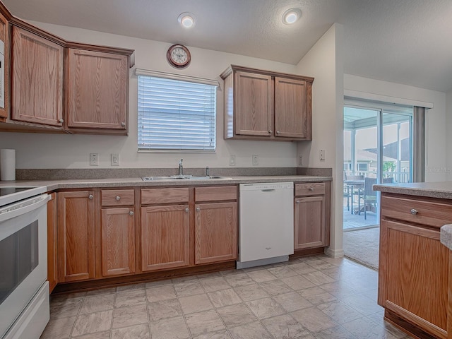 kitchen with a textured ceiling, white appliances, and sink