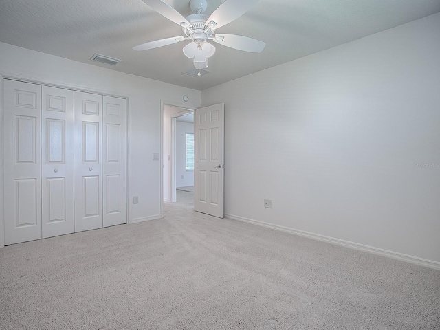 unfurnished bedroom featuring light carpet, a closet, and ceiling fan