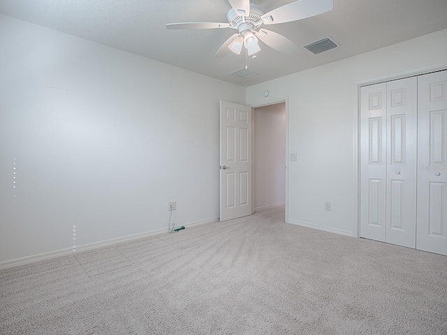 unfurnished bedroom featuring ceiling fan, a closet, and light colored carpet