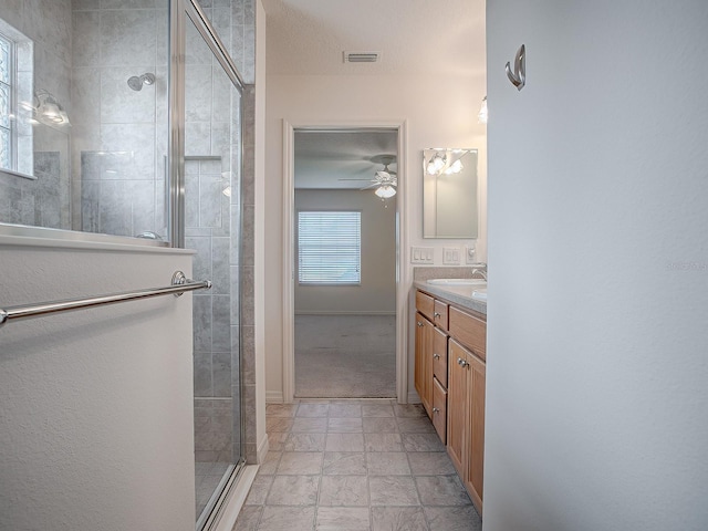 bathroom featuring a textured ceiling, vanity, an enclosed shower, and ceiling fan