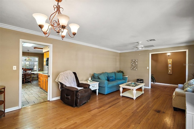 living room featuring ceiling fan with notable chandelier, hardwood / wood-style flooring, and crown molding