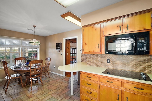 kitchen featuring a kitchen bar, decorative light fixtures, tasteful backsplash, and black appliances