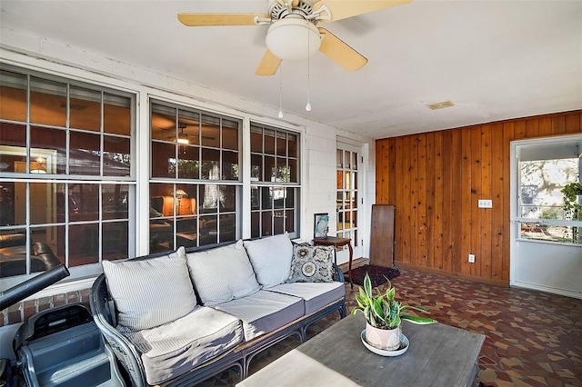 interior space with ceiling fan and wood walls