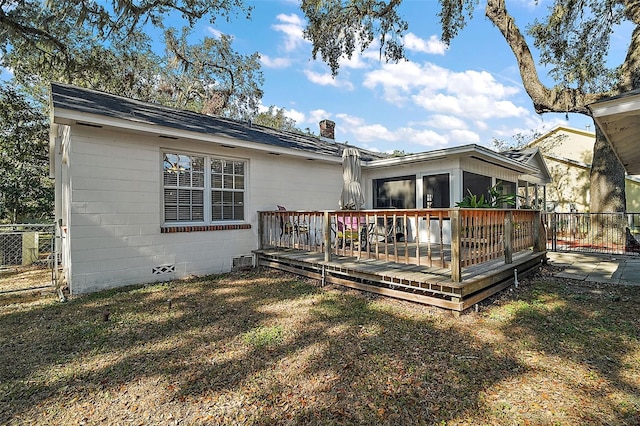 back of house with a lawn, a wooden deck, and a sunroom