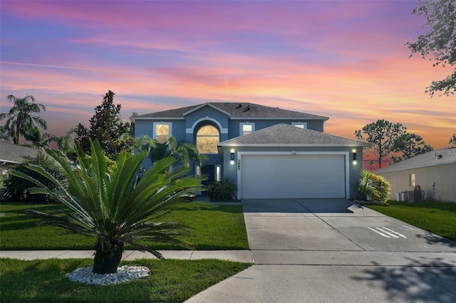 view of front of property featuring a lawn, central AC, and a garage