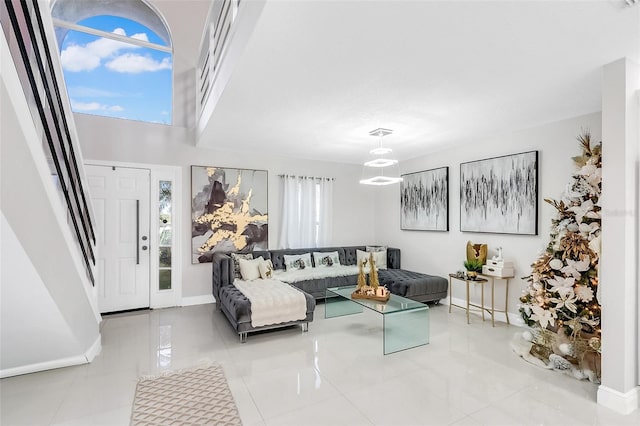 tiled living room featuring a healthy amount of sunlight, a towering ceiling, and an inviting chandelier