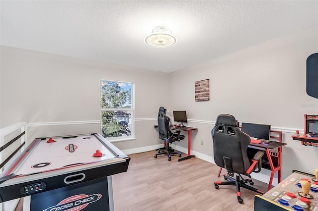 playroom with a textured ceiling and light wood-type flooring