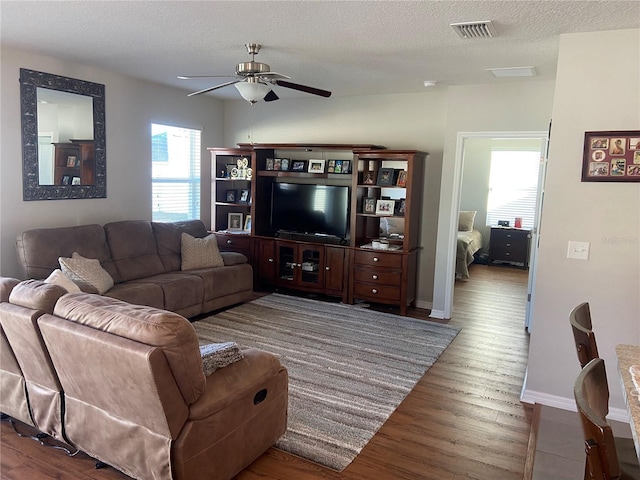 living room with ceiling fan, hardwood / wood-style floors, and a textured ceiling