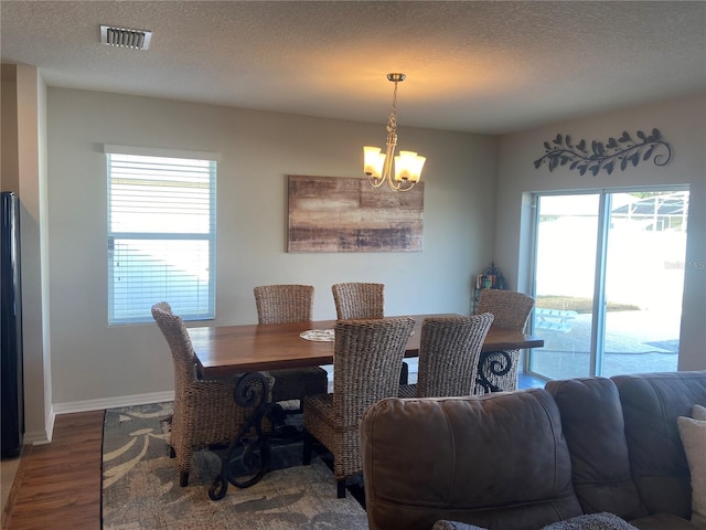 dining room with hardwood / wood-style flooring, plenty of natural light, a textured ceiling, and an inviting chandelier