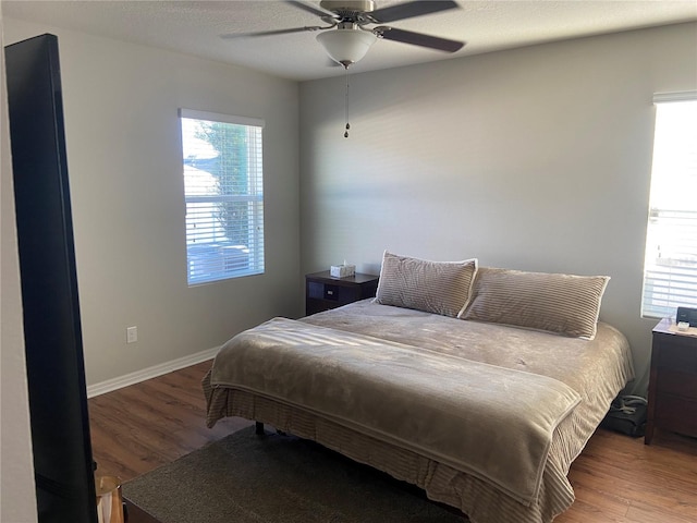 bedroom with dark hardwood / wood-style floors, ceiling fan, and a textured ceiling