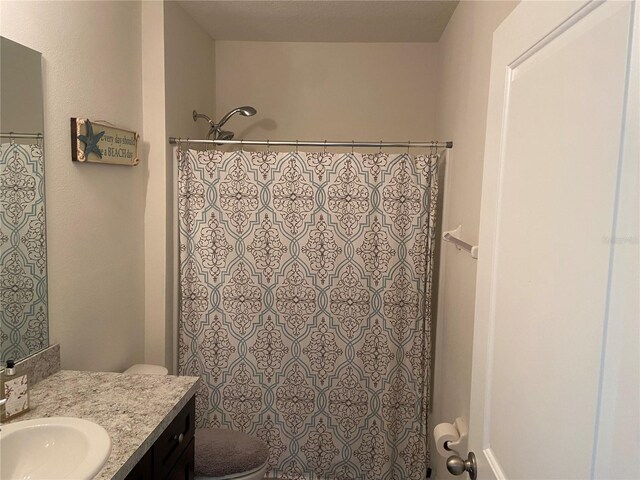 bathroom featuring vanity, toilet, and curtained shower