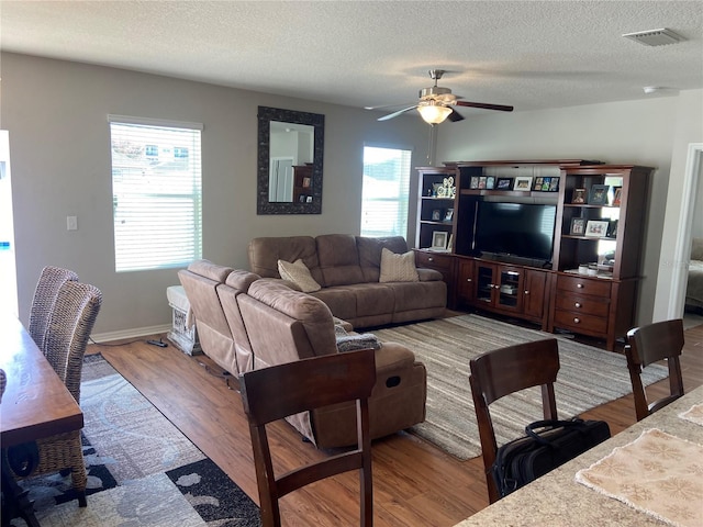 living room with ceiling fan, plenty of natural light, a textured ceiling, and hardwood / wood-style flooring