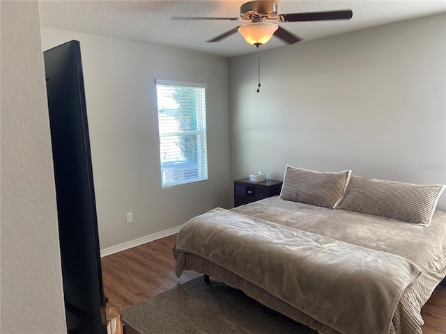 bedroom featuring ceiling fan, dark wood-type flooring, and a textured ceiling